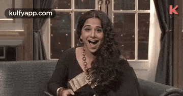 a woman is laughing while sitting on a couch .