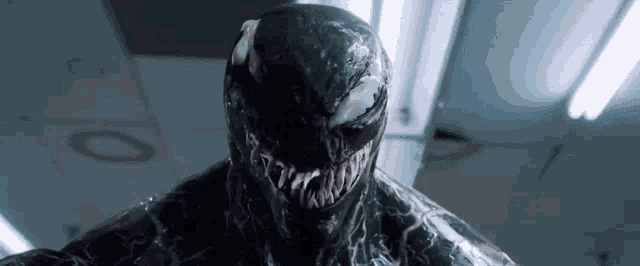 a close up of venom 's face in a dark room with lights on the ceiling .