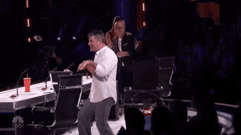 a man in a white shirt is dancing on a stage while a woman watches .