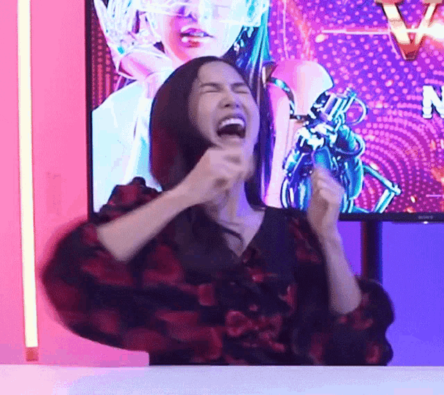 a woman is screaming in front of a tv screen with the letter n on it