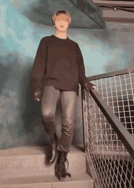 a person is standing on a set of stairs wearing a black sweater and black pants .