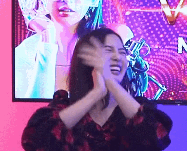 a woman is making a funny face in front of a television screen .
