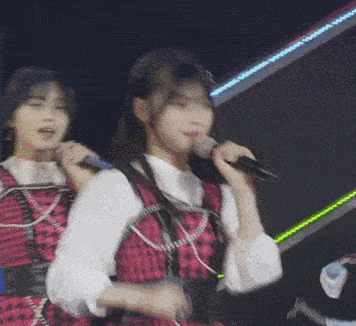a woman singing into a microphone while another woman stands behind her