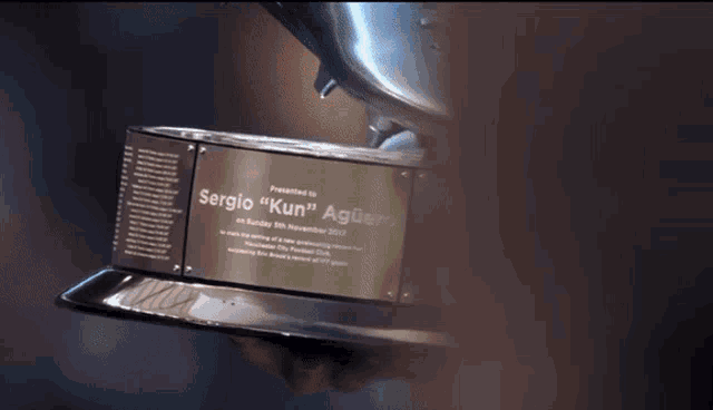 a person holding a trophy that says sergio " kun " on it