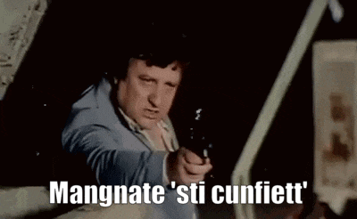 a man in a suit is pointing a gun at the camera with the words `` mangnate sti cunfiett '' behind him .