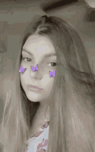 a girl with purple butterflies on her face is looking at the camera .