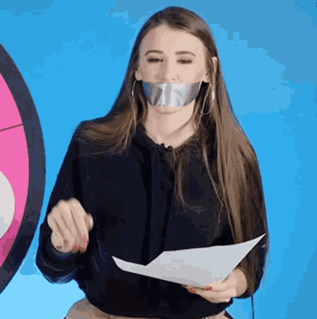 a woman with duct tape on her mouth holding a piece of paper .