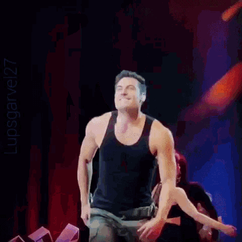 a man in a black tank top is performing on stage