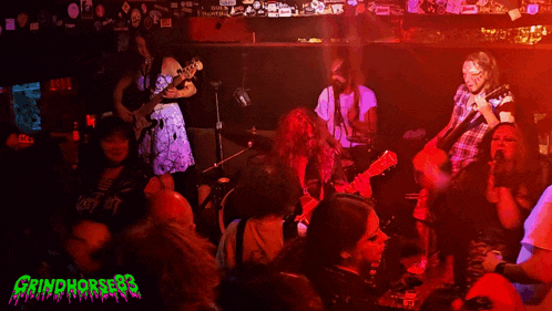 a group of people playing instruments in a dark room with the words grindhorses on the bottom right