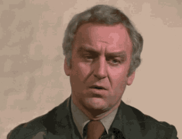 a man in a suit and tie is making a serious face