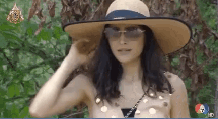 a woman wearing a straw hat and sunglasses stands in front of a screen that says 7 hd