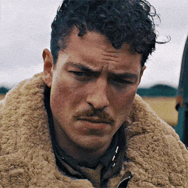 a close up of a man with a mustache wearing a fur coat