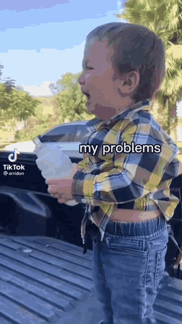 a little boy is crying while holding a bottle of water and a tiktok video is behind him
