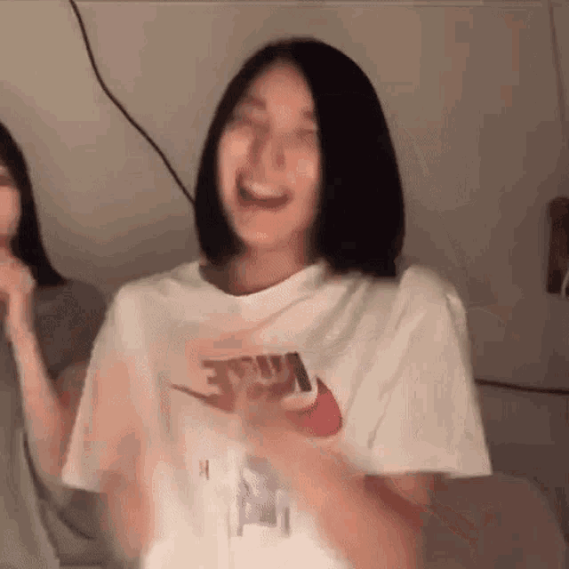 a woman wearing a white nike t-shirt is laughing and dancing .