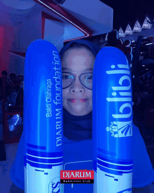 a girl wearing glasses is holding two blue balloons that say diarum foundation and blibli