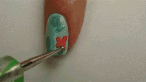a close up of a person 's nails being painted with blue and red nail polish .