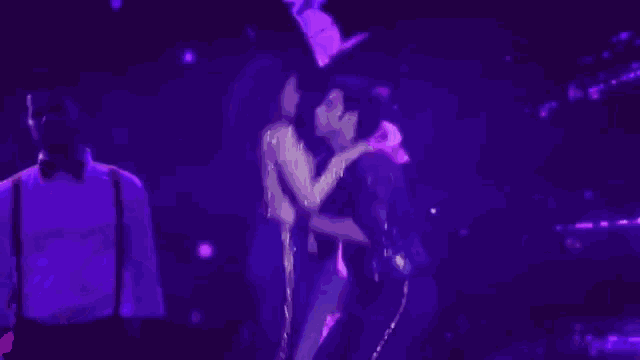 a man is holding a woman in his arms on a stage in a dark room .