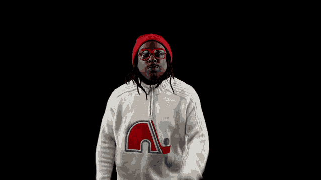 a man wearing a red hat and sunglasses is wearing a white sweater with the letter a on the front
