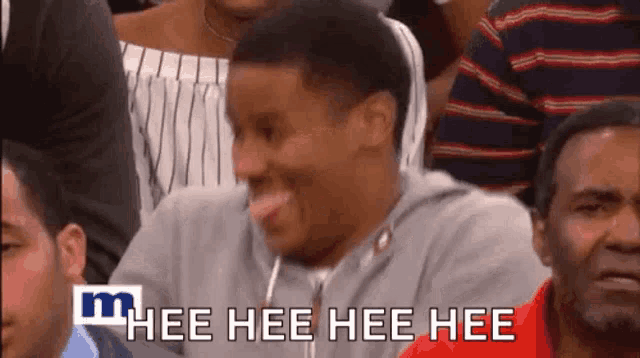 a man is sticking his tongue out while sitting in a crowd and the words hee hee hee hee are above him