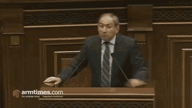 a man in a suit and tie is giving a speech at a podium with armtimes.com on the bottom