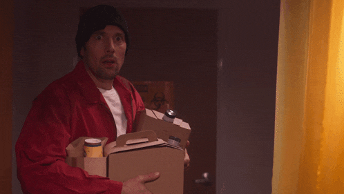 a man in a red jacket is holding a cardboard box and a can of soda