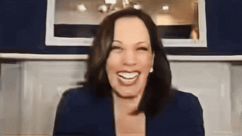 a woman in a blue jacket is smiling in front of a blue wall