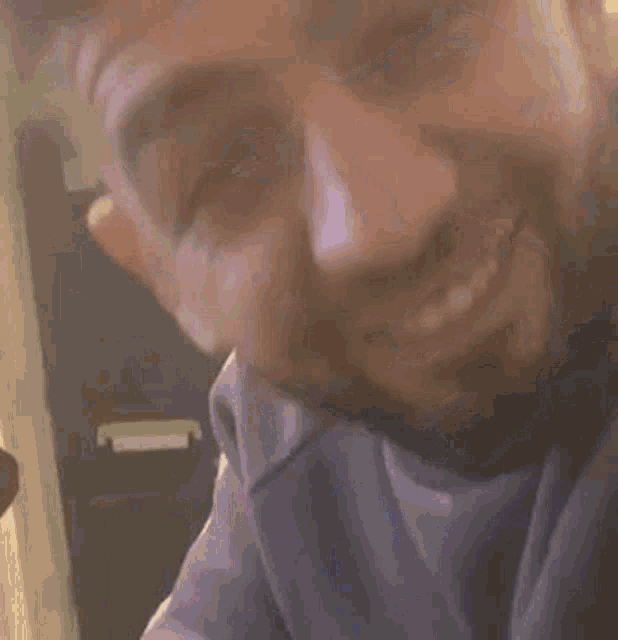 a man with a beard is smiling for the camera in a room .