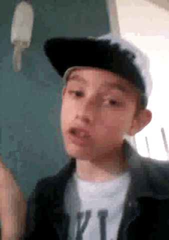 a young boy wearing a hat and a t-shirt with the letter t on it