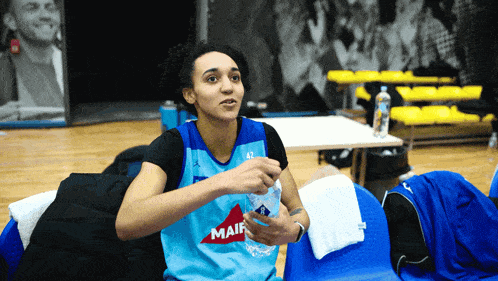 a woman wearing a mair jersey sits in a chair