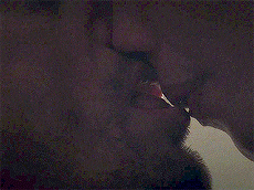 a man is lighting a cigarette with a lighter while a woman kisses him .