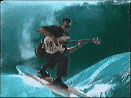 a man is playing a guitar while riding a wave on a surfboard in the ocean .