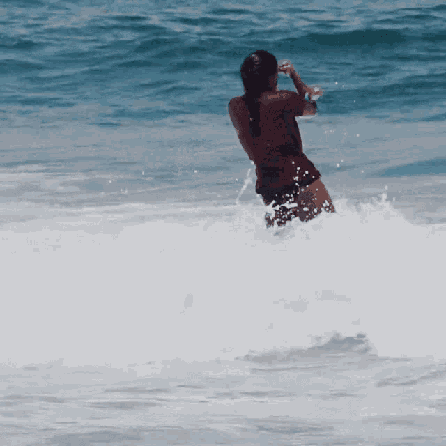 a woman in a red shirt stands in the ocean