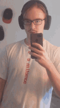 a man wearing headphones takes a selfie with a supreme shirt