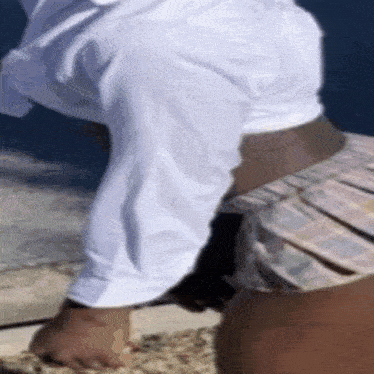 a person wearing a white shirt and plaid skirt is kneeling on the ground .