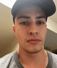 a young man wearing a hat and a gray shirt looks at the camera .