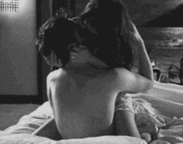 a man and a woman are kissing on a bed .