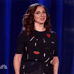 a woman is standing on a stage wearing a black shirt with hearts on it .