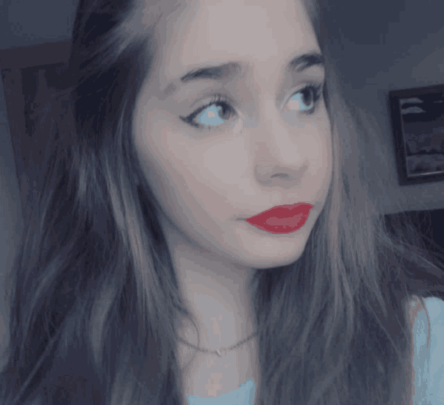 a girl with long hair and red lipstick is looking at the camera
