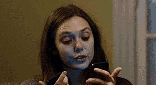 a close up of a woman looking at a cell phone with a watermark that says ' debtielvoer ' on it