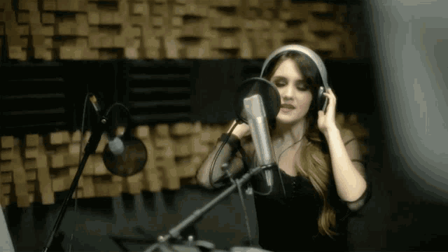 a woman is singing into a microphone in a recording studio
