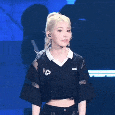 a girl with blonde hair is wearing a black crop top and a white shirt .
