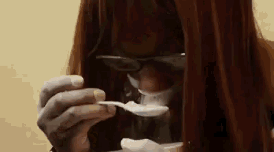 a woman is eating ice cream with a spoon while wearing sunglasses .