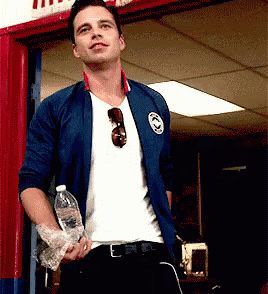 a man in a blue jacket is holding a bottle of water in his hand .
