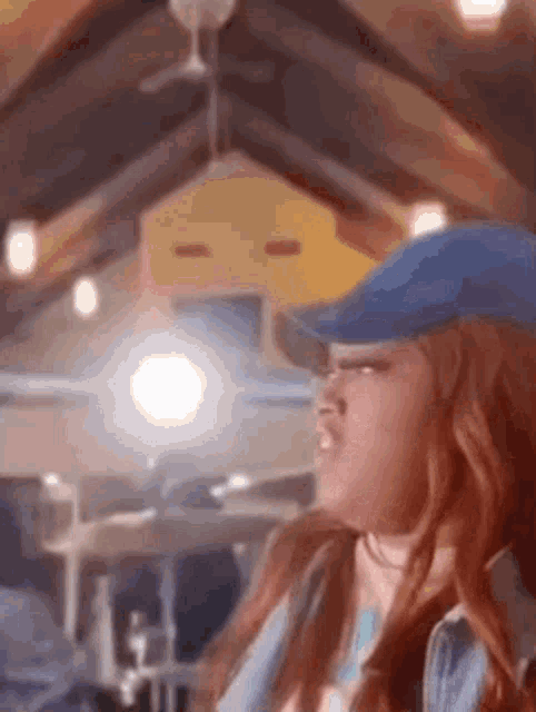 a woman with red hair is wearing a blue hat and a denim jacket .
