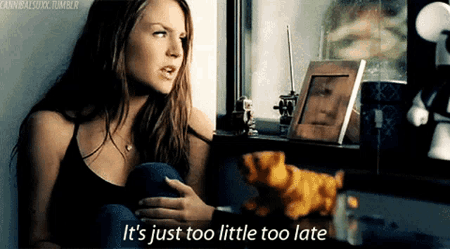 a woman sitting in front of a window with the words it 's just too little too late below her