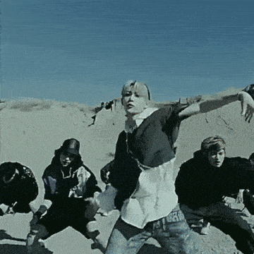 a group of people are dancing in the desert with a blue sky in the background .
