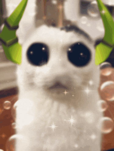 a white cat with green horns and big eyes