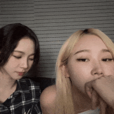 two girls are sitting next to each other with one covering her mouth