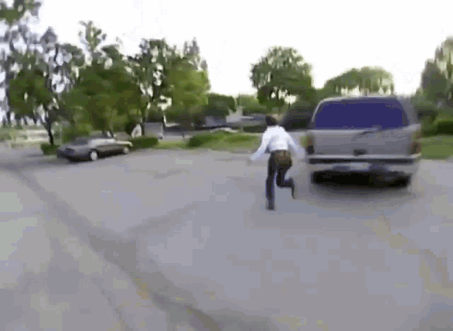 a man is running away from a car that is driving down the road .
