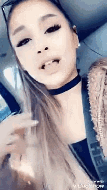 ariana grande is sitting in the back seat of a car with her tongue sticking out .